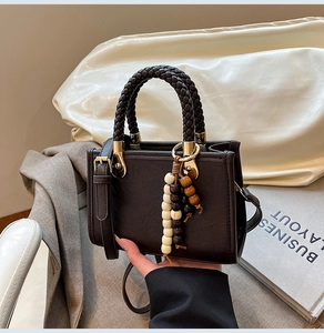 Detail of dark brown vintage handbag with woven handle and beaded pendant decoration
