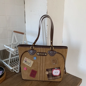 Detail of vintage brown tote bag with cartoon patches and polished leather handles
