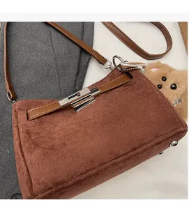 Detail view of brown matte leather handbag featuring silver twist lock and suede texture