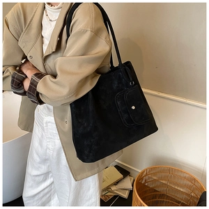 Detail of black matte tote bag with small front buckle pocket worn on shoulder