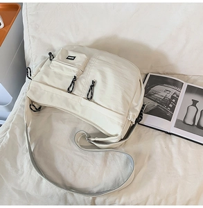 Détail du sac bandoulière blanc cassé avec poche frontale et tirettes de zip en corde