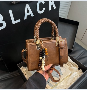 Detail of vintage brown leather bag with woven handle and colorful beaded tassel