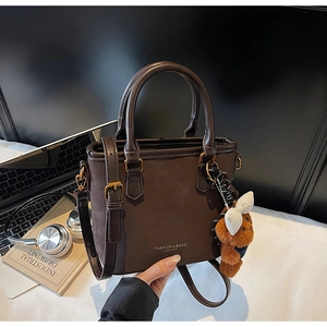 Close-up of vintage brown leather handbag with round handles and cute bear charm