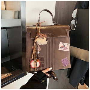 Détail d'un sac vintage marron avec pendentif chien et écussons décoratifs stylés