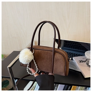 Close-up of brown suede bowling bag with white fur pompom and pearl metal chain