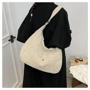 Détail d'un sac bandoulière croissant blanc crème avec texture plissée et bouton argent