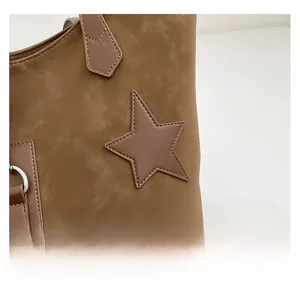 Makroaufnahme der braunen Veloursleder-Tasche mit Stern-Patch und Metall-D-Ring-Details
