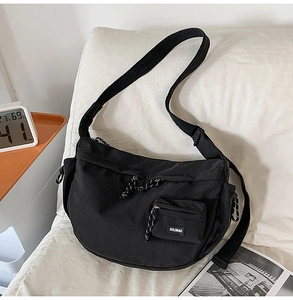 Détail du sac bandoulière croissant en nylon noir avec cordon et poche avant zippée