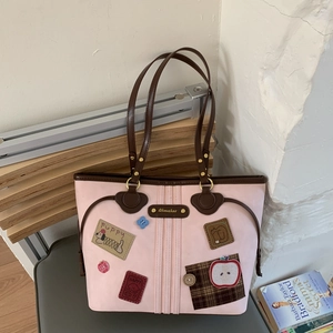 Close-up of pink tote bag featuring cute cartoon puppy patches and metal logo plate