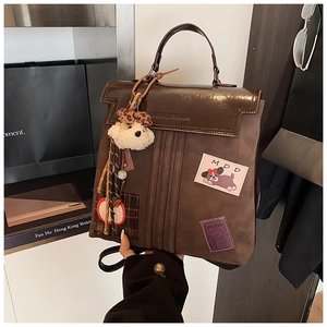 Détail d'un sac à dos vintage marron avec écussons de dessins animés et charme de chien
