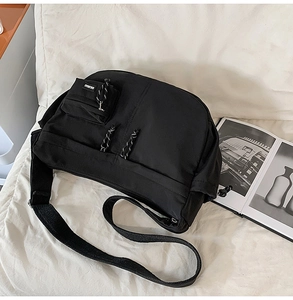 Détail d'un sac bandoulière en nylon noir avec poche zippée et tirette tissée décorative