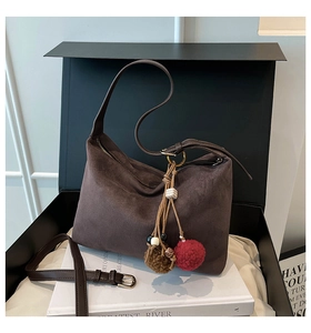 Detail of dark brown suede shoulder bag with ethnic beaded tassel and long strap