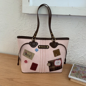 Detail of pink retro tote bag featuring puppy patches and premium matte leather texture