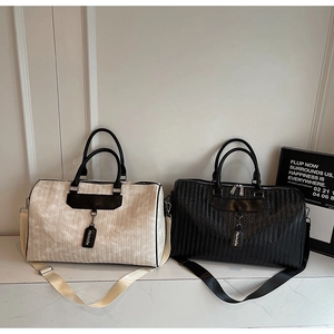 Detail of woven travel bags in cream and black with leather straps and handles