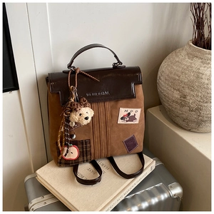 Détail du sac à dos vintage marron avec pendentif ours et écussons brodés de style