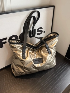 Sac fourre-tout matelassé doré avec lanières noires et étiquette de mode sous lumière
