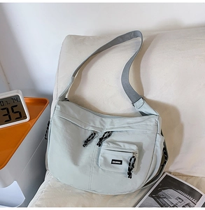 Gros plan détaillé du sac croissant en nylon vert menthe avec bandoulière grise sur sofa