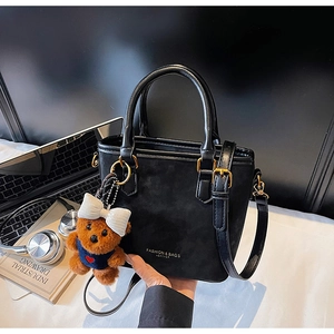 Detail of black tote bag with matte and glossy leather texture and gold hardware