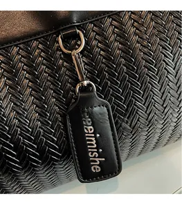 Close-up of black woven faux leather bag with silver metal hook and textured detail