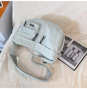 Détail de sac bandoulière en nylon vert clair avec poche zippée et logo tissé stylé