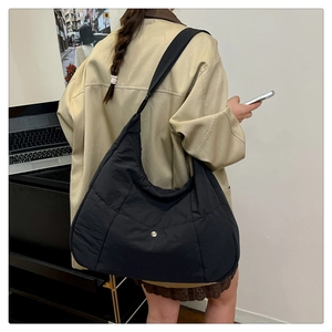 Vue latérale d'un grand sac bandoulière matelassé noir en nylon porté par un mannequin