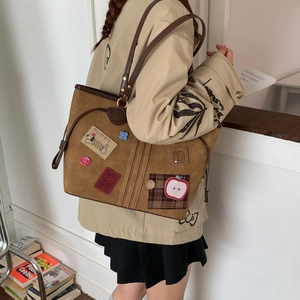 Detail of vintage brown suede tote bag with cartoon patches on a model