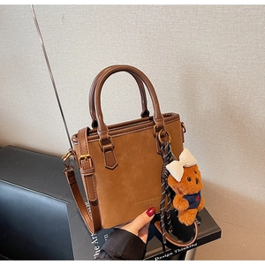 Detail of vintage brown bucket bag featuring bronze hardware and cute teddy bear charm