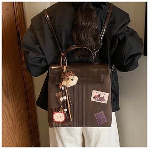 Détail du sac à dos vintage marron avec écussons brodés et pendentif ours en peluche