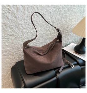 Detail of vintage brown suede dumpling bag with leather strap on a sofa