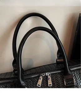 Detail of black woven travel bag with comfortable double handles and silver dual zippers
