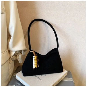 Detail of black suede shoulder bag featuring decorative tri-color beaded charms on side
