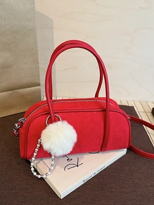 Red suede Boston bowling bag with white fur ball charm and leather shoulder strap