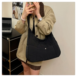Détail du sac hobo en nylon matelassé noir avec poche à pression et large bandoulière
