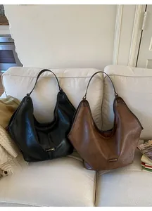 Detail of vintage tote bags in black and brown on a white sofa with metal logo hardware