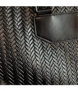 Detail of black woven shoulder bag with herringbone texture and premium leather patch
