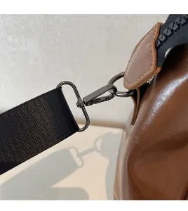 Détail du crochet métallique et de la sangle en nylon sur le sac de voyage en cuir