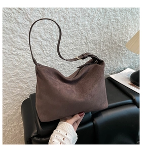 Detail of dark brown suede hobo bag with adjustable strap on a minimalist studio set