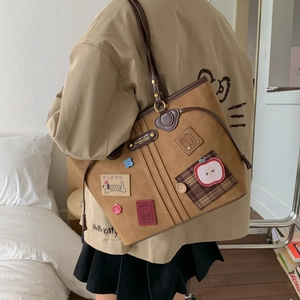Detail of vintage brown tote bag featuring puppy embroidery and retro college style patches