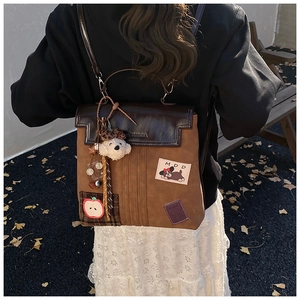 Détail d'un sac à dos vintage marron avec broderie de dessin animé et ours en peluche