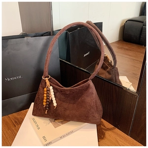 Close-up of coffee brown suede shoulder bag with vintage wood bead tassel detail