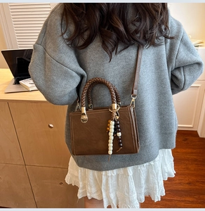Detail of vintage brown crossbody bag with woven handles and ethnic beaded tassel charm