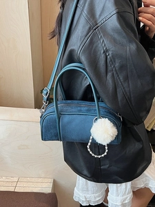Dark blue cylinder bowling bag in faux suede featuring a stylish plush ball pendant