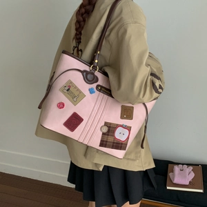 Detail of pink leather tote bag featuring cute puppy and apple embroidery patches