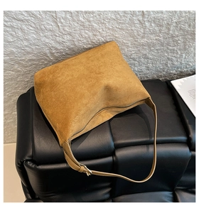 Detail view of the suede shoulder bag featuring a smooth zipper and metal buckle strap