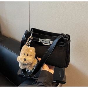 Detail of black matte shoulder bag with silver lock and plush dog charm accessory