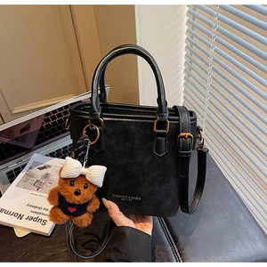 Detail of black textured bucket bag with teddy bear charm and gold ring hardware