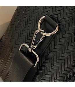 Close-up of silver metal swivel hook and black woven shoulder strap on travel bag