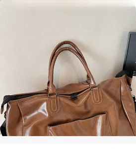 Gros plan du sac de voyage en cuir PU marron avec poignées solides et poche zippée