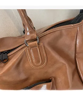 Détail du sac de voyage en cuir marron avec fermeture éclair noire et anneau en D métal