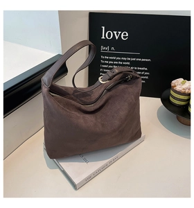 Detailed view of dark brown suede hobo bag texture and golden hardware on a book